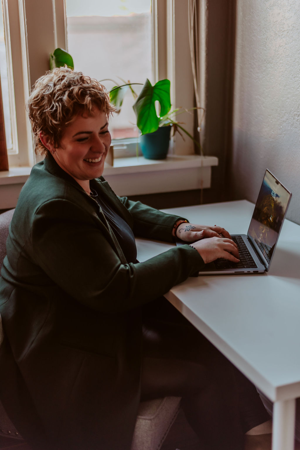 Kim, CEO of KD Graphics, smiling off to the side while sitting at a desk with a laptop.